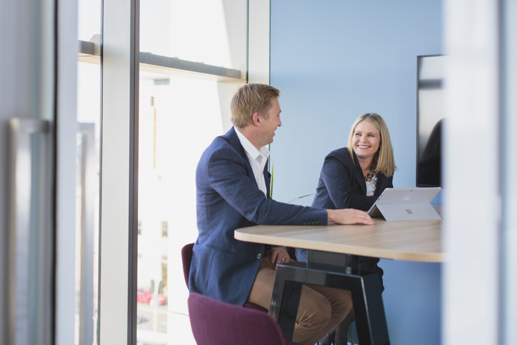 man and woman talking in front of computer