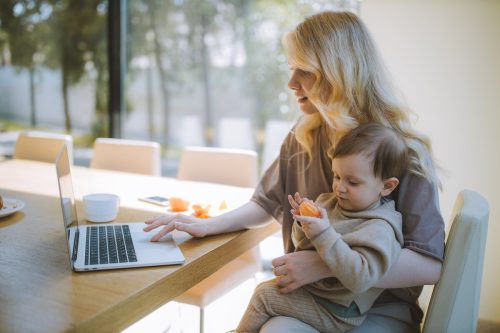 Mother working on laptop with baby on her knee